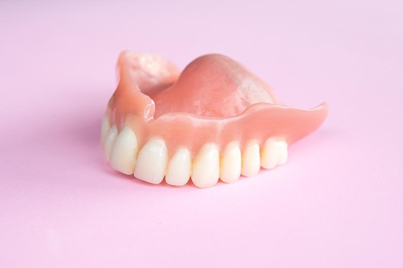 closeup of dental prosthesis on a pink background